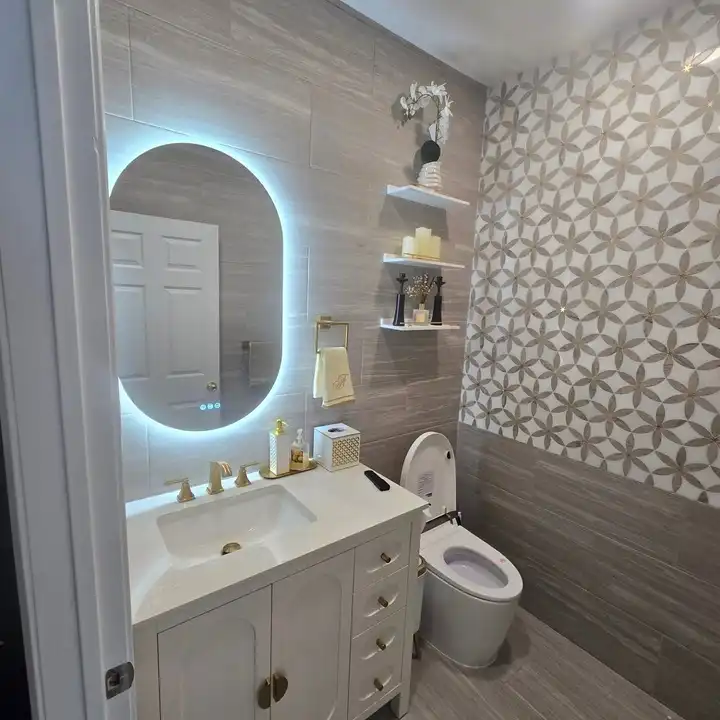 Backlit oval mirror with two floating shelves on a patterned tile wall