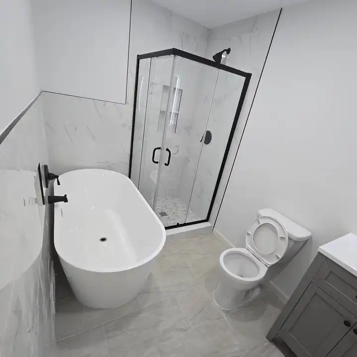 Freestanding tub beside a black-framed corner shower on a plank floor