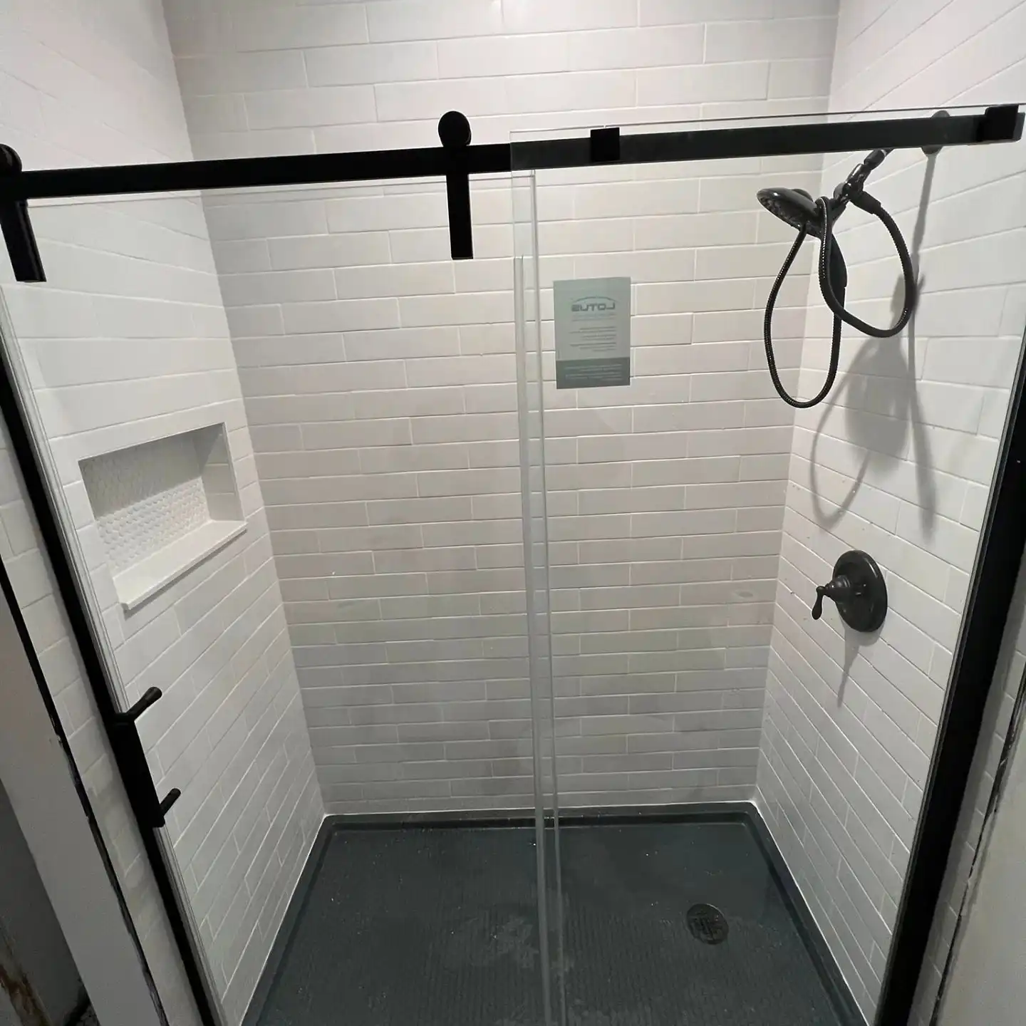 The finished white subway shower with a black-framed sliding door