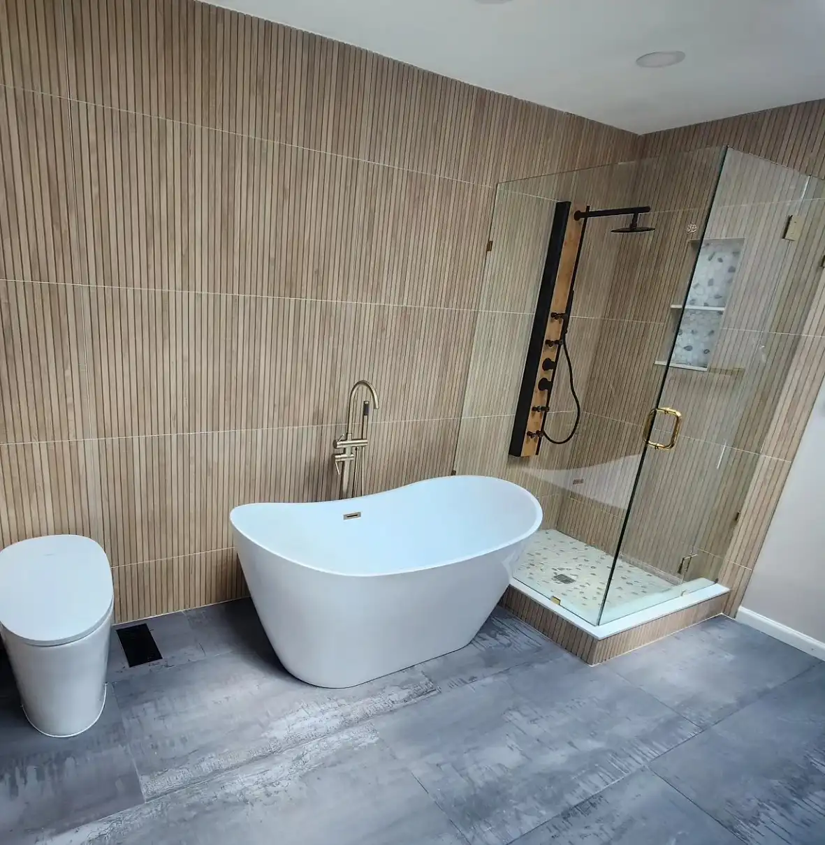 Freestanding tub against a wood-look tile wall with a glass corner shower, finished bathroom