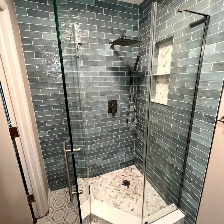 Close view of the glossy sea-green subway tile with a rain head above