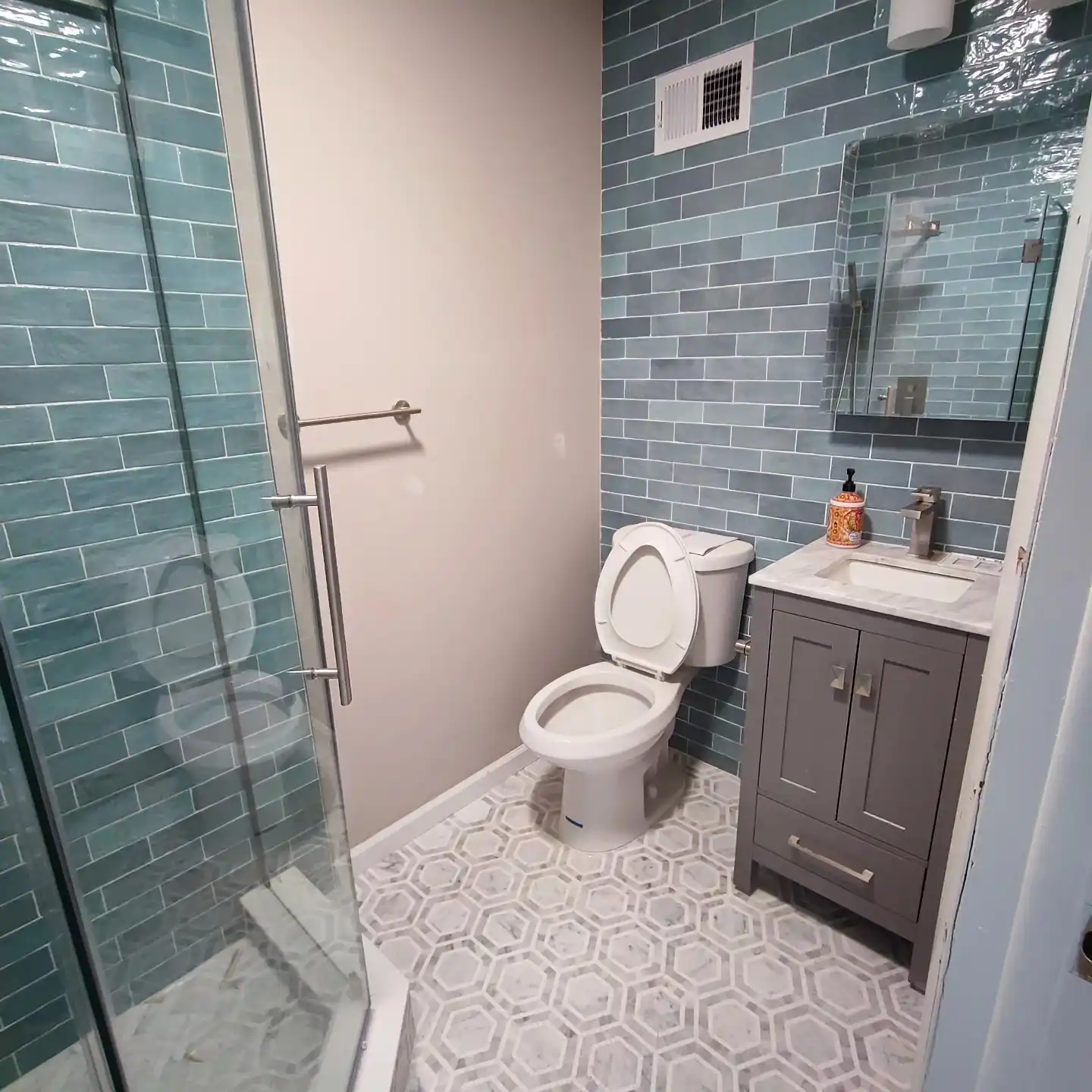 The finished green subway shower with glass and a hexagon floor